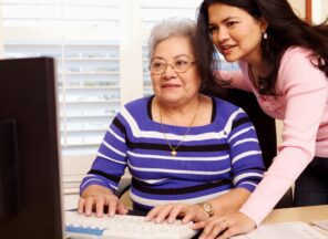 A woman helping an older woman on a computer.